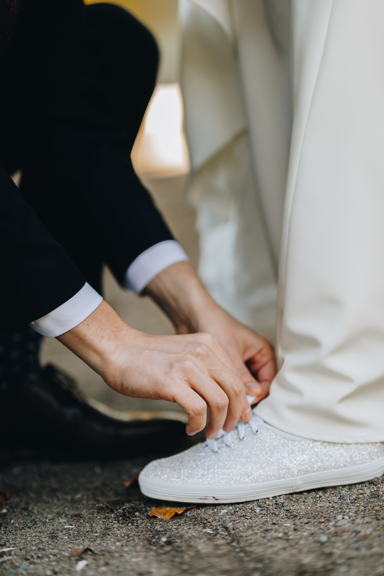 Fun candid Prospect Park wedding photos while groom ties bride's shoe