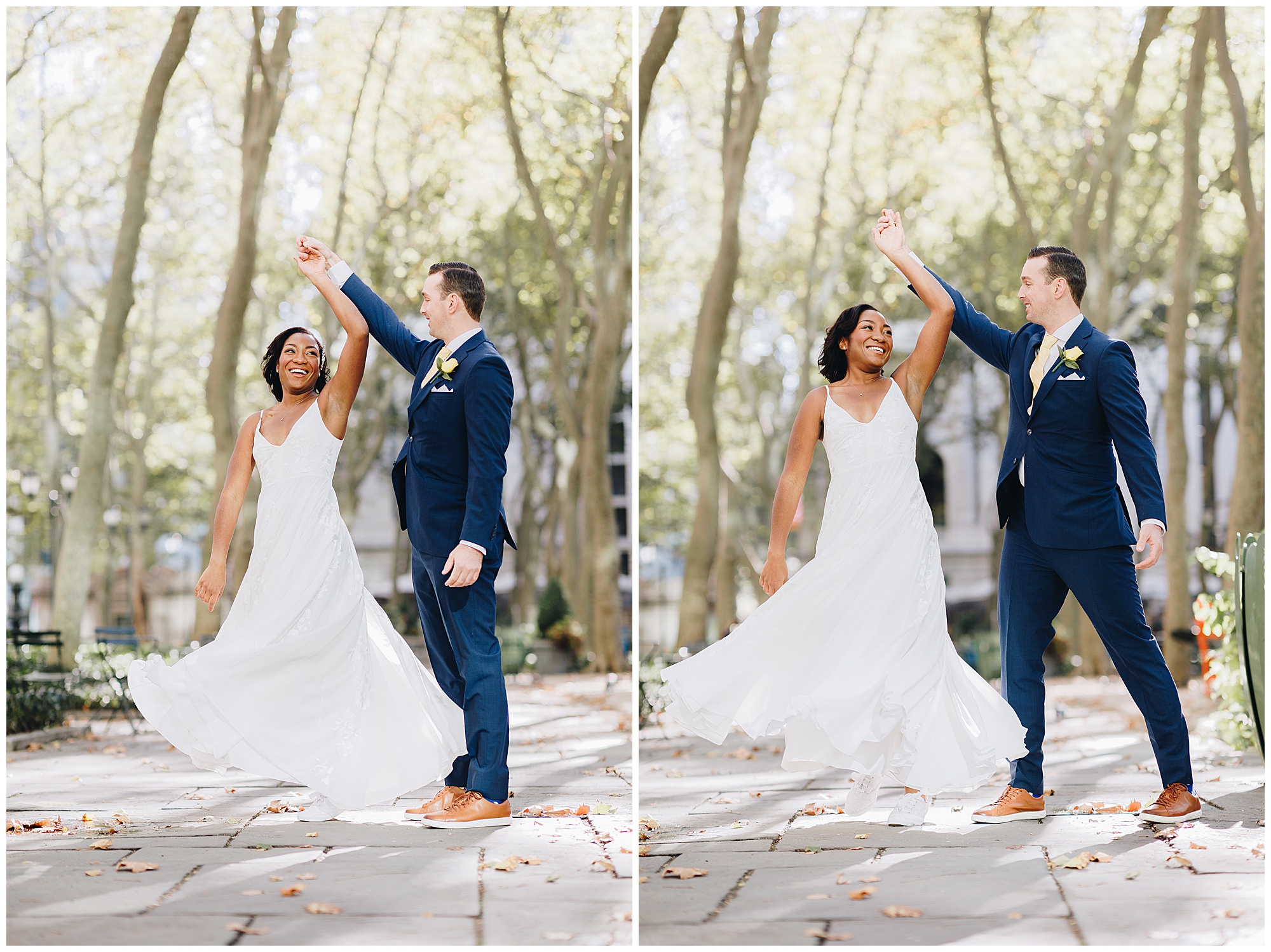 A couple in wedding attire dances outdoors on a tree-lined path during their Wagner Cove elopement. The bride twirls in a flowing white dress, smiling, while the groom in a dark blue suit holds her hand and smiles back.