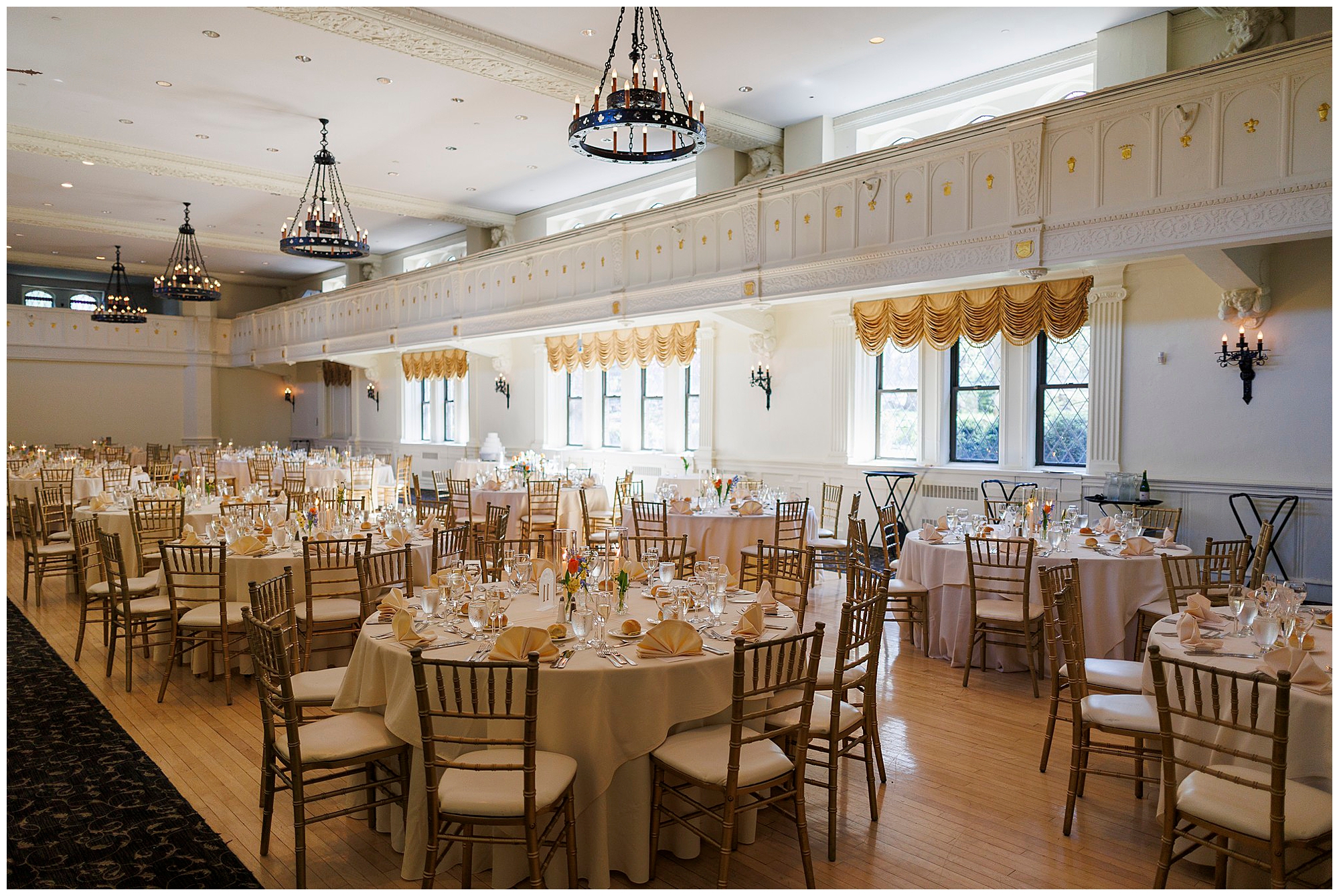 Elegant ballroom wedding reception with round tables, gold linens, and formal place settings, photographed by Hudson Valley wedding photographers specializing in upscale event photography and videography