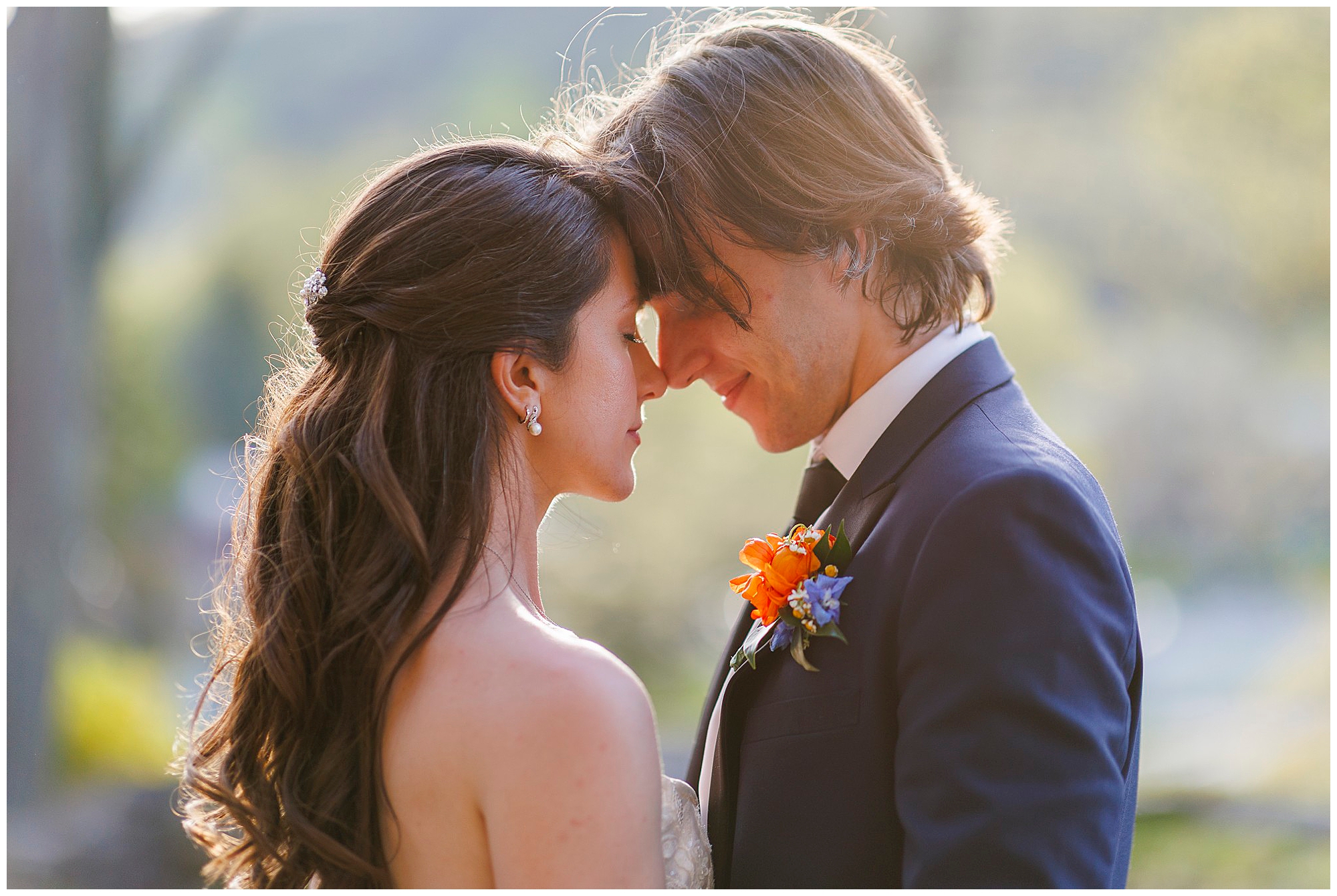 Romantic bride and groom moment captured by Hudson Valley wedding photographers, featuring intimate forehead touch with orange boutonniere detail.