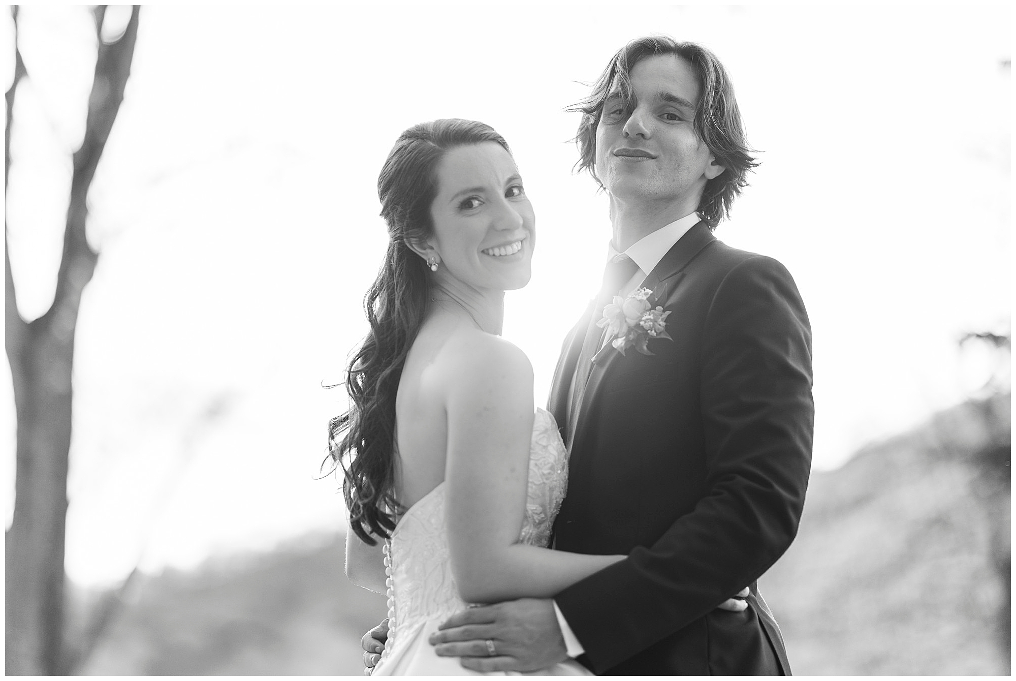 Black and white wedding portrait of a bride and groom smiling at the camera in a scenic outdoor setting, captured by Hudson Valley wedding photographers specializing in romantic couple photography and videography