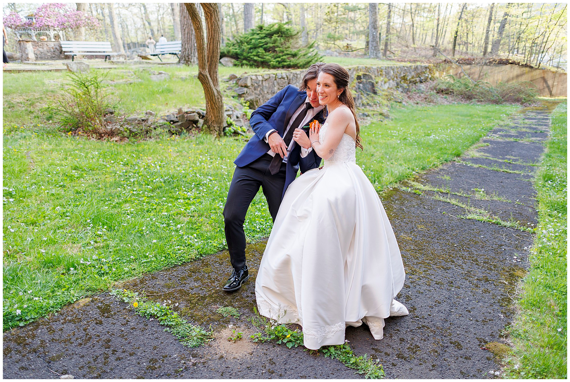 Joyful bride and groom running together on a tree-lined path during their Hudson Valley wedding, captured by a professional Hudson Valley wedding photography team in a scenic outdoor garden setting.