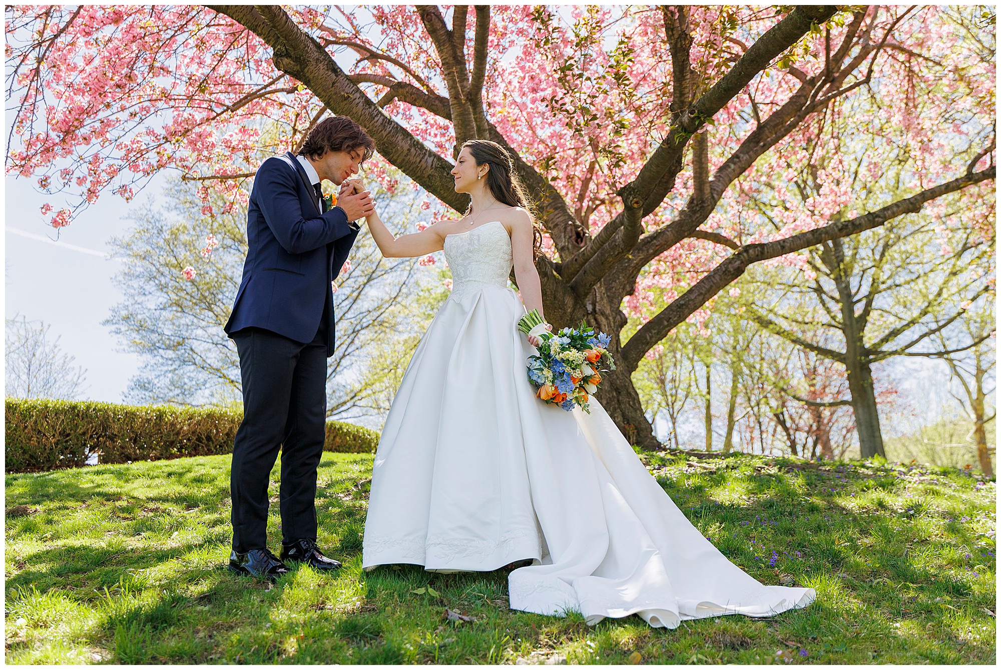 Couple standing close together beneath cherry blossom trees at their Hudson Valley spring wedding