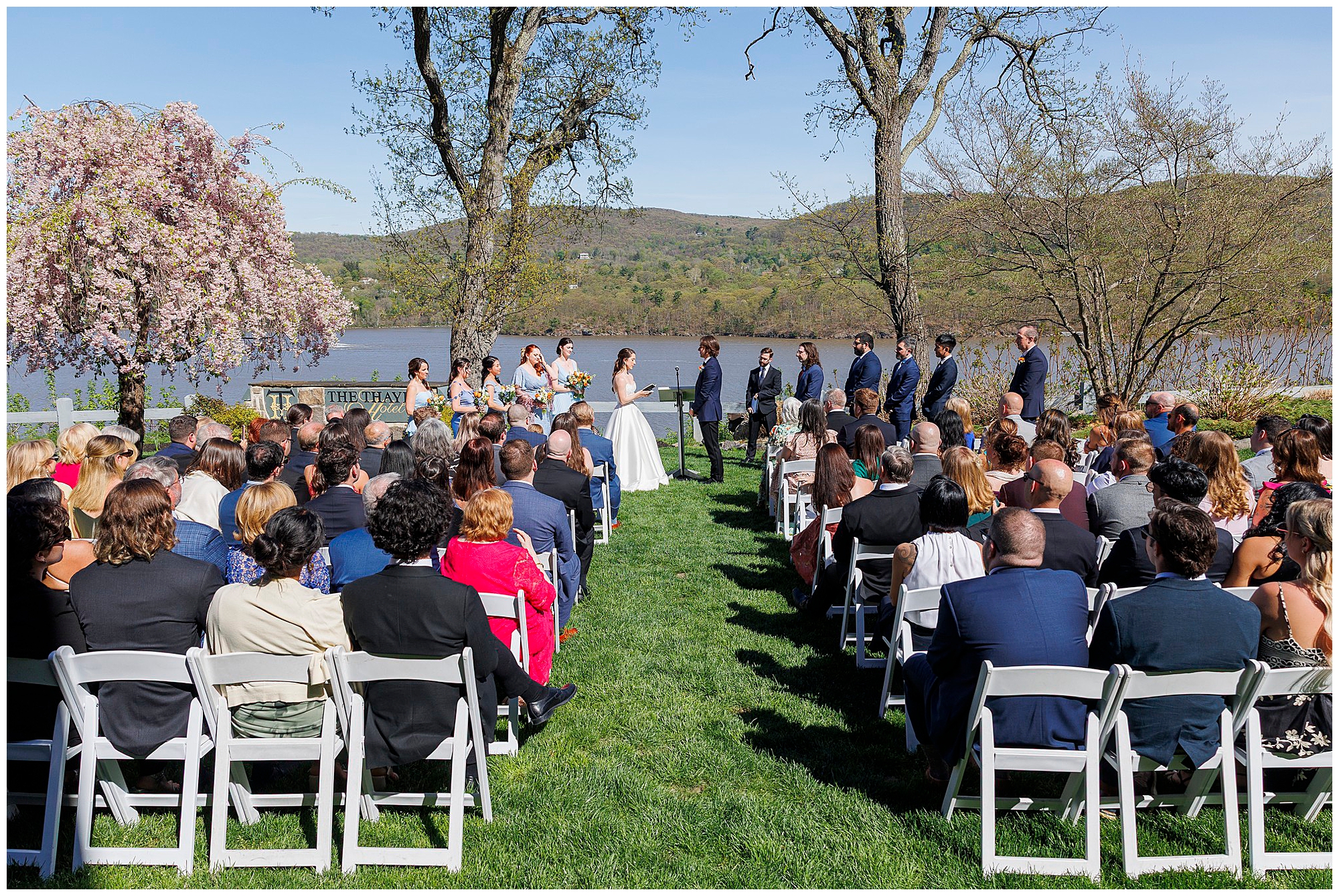 Wide angle shot of outdoor wedding ceremony at West Point with all guests seated on a sunny spring day