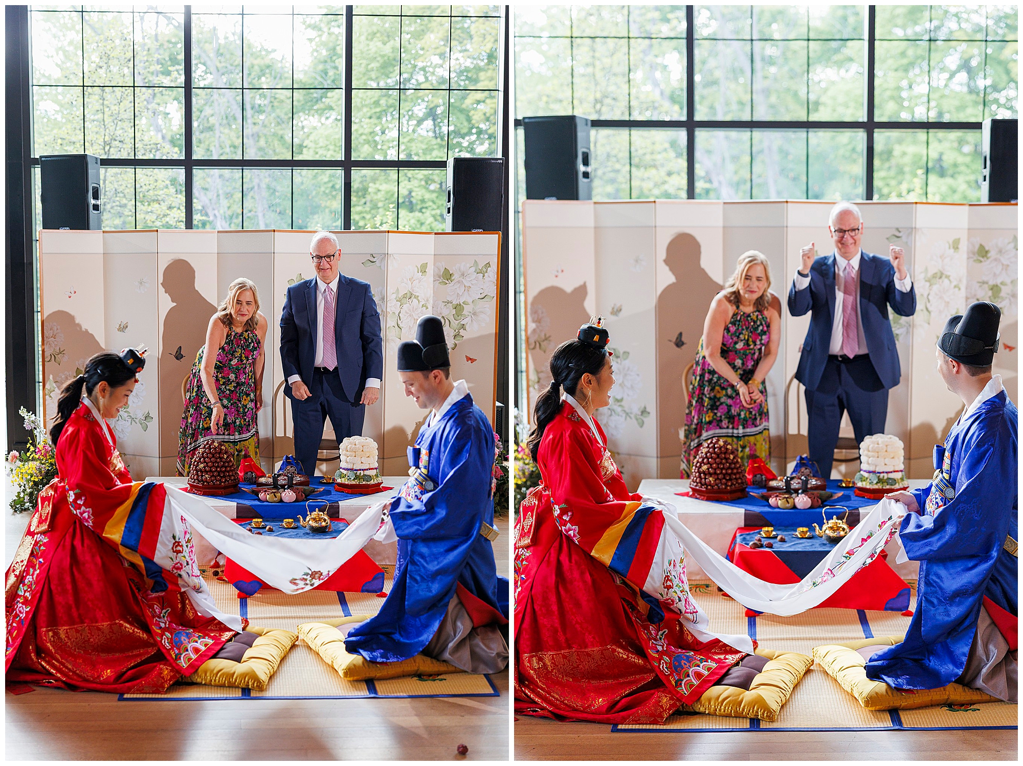 Two couples in traditional Korean dress kneel by a low table with food, performing a ceremony indoors at a roundhouse wedding. A woman and man stand behind the table; the man raises his arms, smiling. Large windows and a decorative screen are in the background.