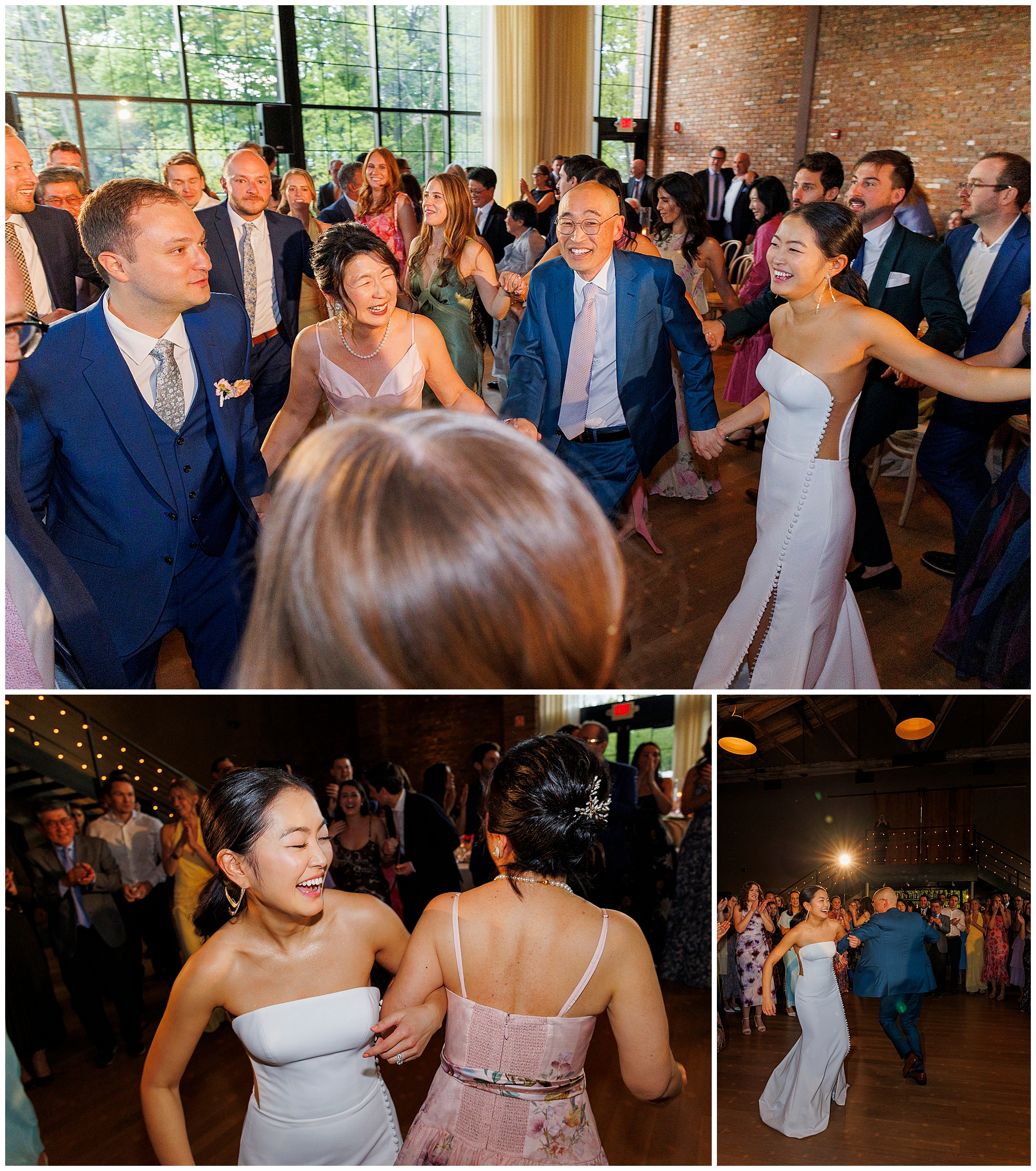 A group of people, dressed in formal attire, joyfully dance together at a roundhouse wedding reception in a bright, spacious venue with large windows and brick walls. Everyone appears to be celebrating and smiling.