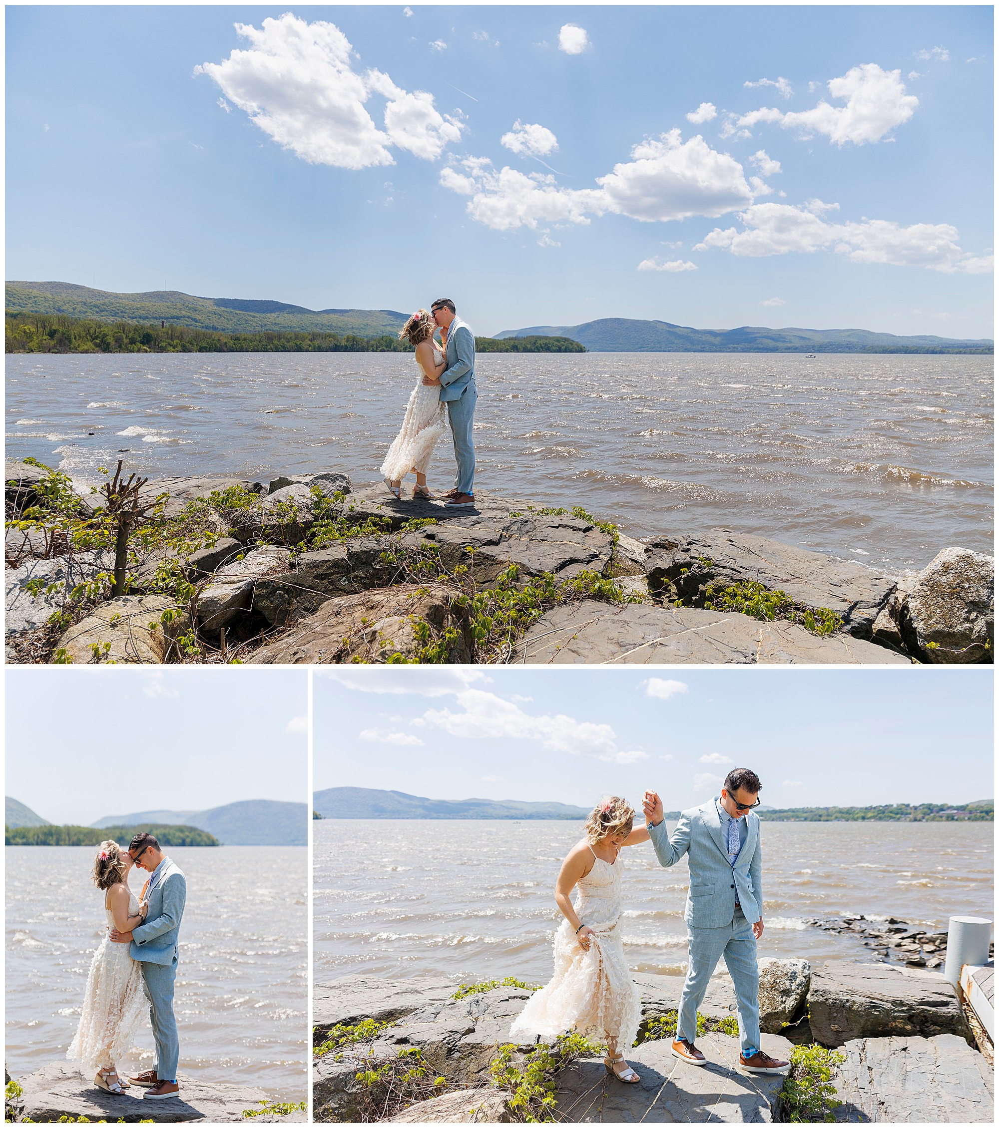 A bride and groom stand on rocky terrain by a large lake, kissing, embracing, and holding hands under a bright, sunny sky with mountains in the background after their Beacon Courthouse elopement.
