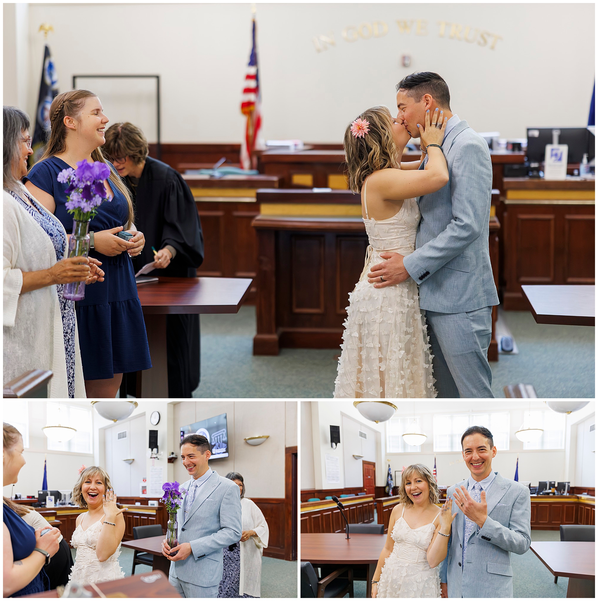 A joyful couple exchanges vows and embraces in a courthouse wedding, surrounded by smiling friends and an officiant, with In God We Trust visible on the wall behind them.