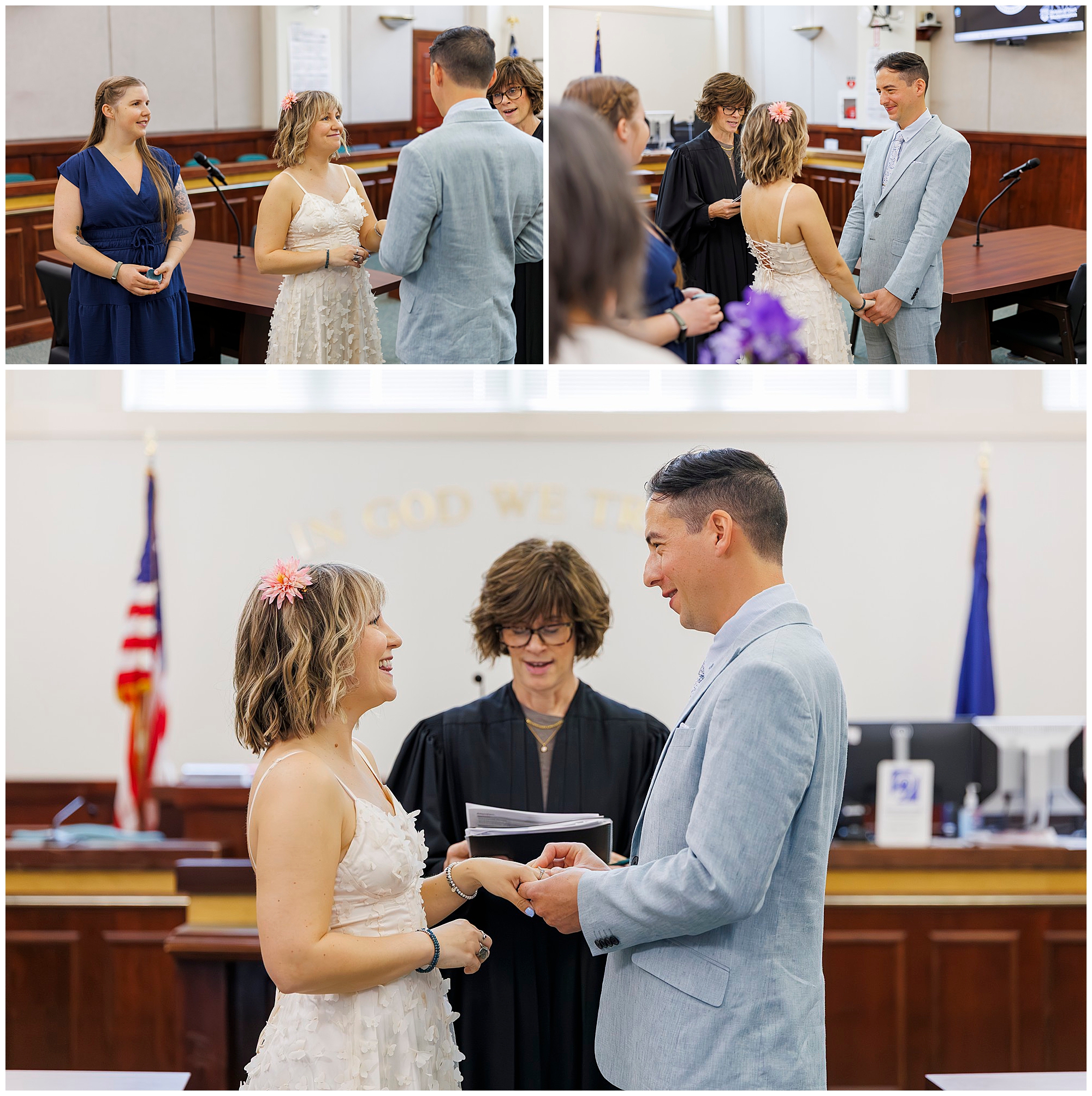 A couple exchanges vows in a courthouse wedding ceremony, smiling at each other as a judge officiates. The bride wears a white dress and the groom a light blue suit; two attendants stand nearby.