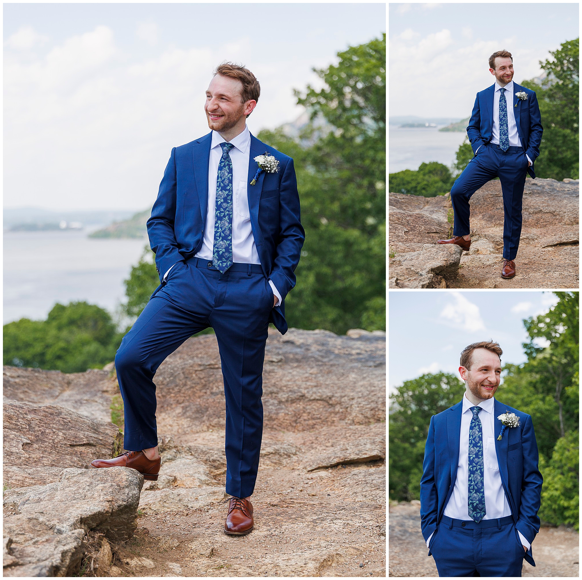 A man in a blue suit, white shirt, and floral tie poses outdoors on rocky terrain after a Beacon City Hall elopement. He is smiling with brown shoes and a small white flower pinned to his jacket, greenery and water in the background.