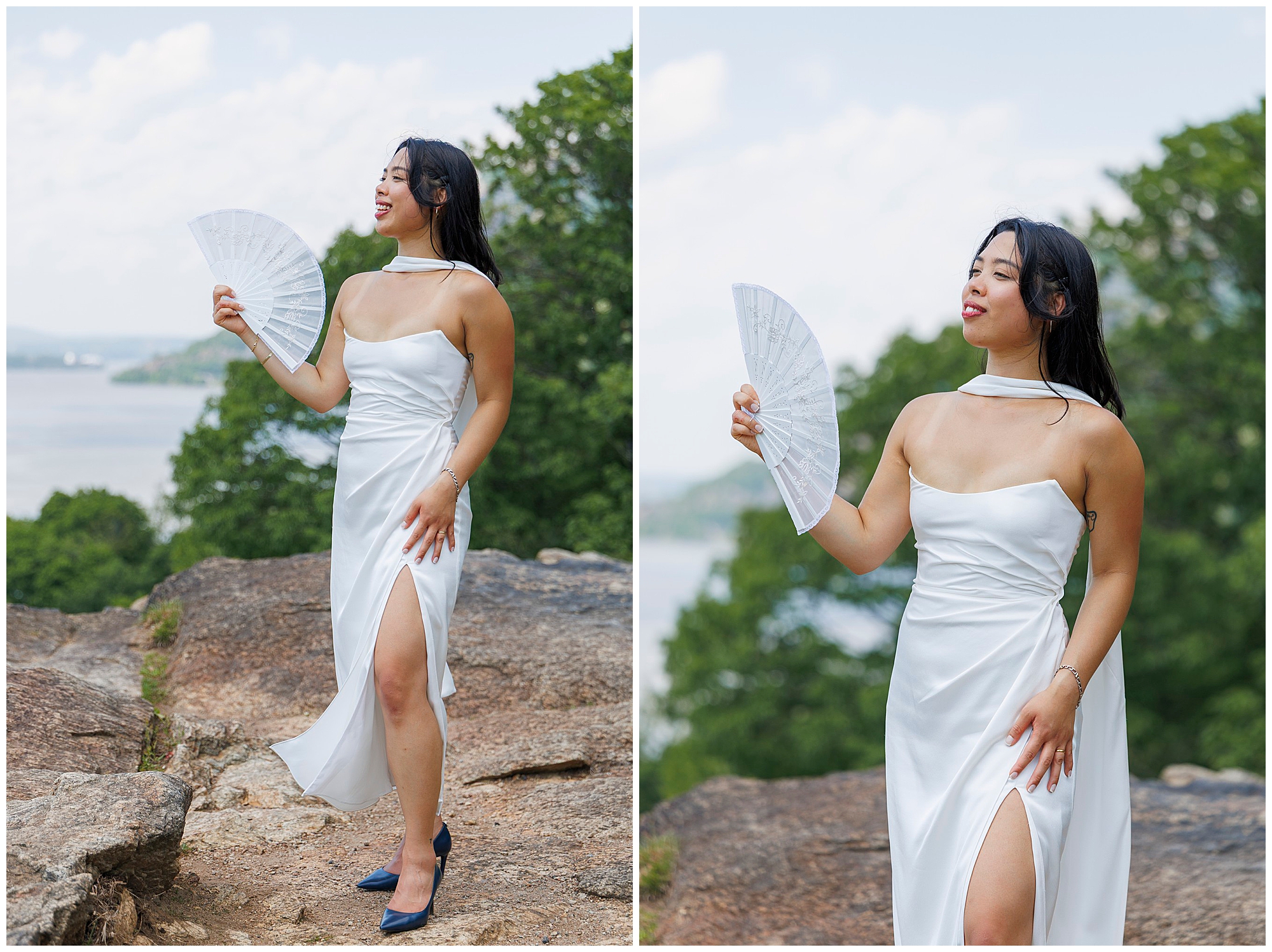 A woman in a white dress with a high slit stands outdoors on rocky ground, holding a white fan—perfect for a Beacon City Hall elopement. Trees and a body of water are visible in the background under a bright sky.