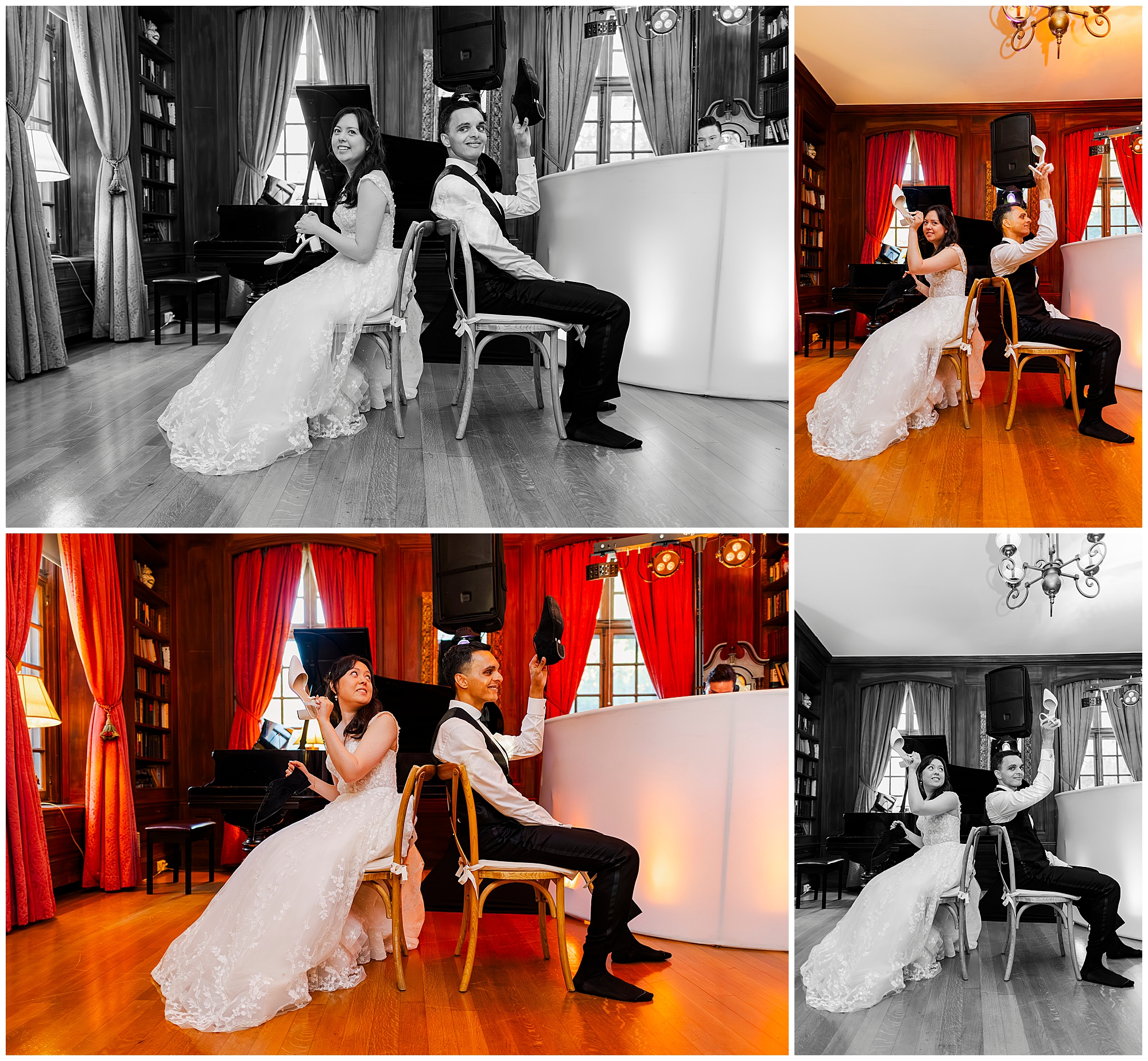 A bride and groom sit back-to-back on chairs, holding up each other’s shoes and smiling during a wedding shoe game in a warmly lit room with red curtains and wooden floors.