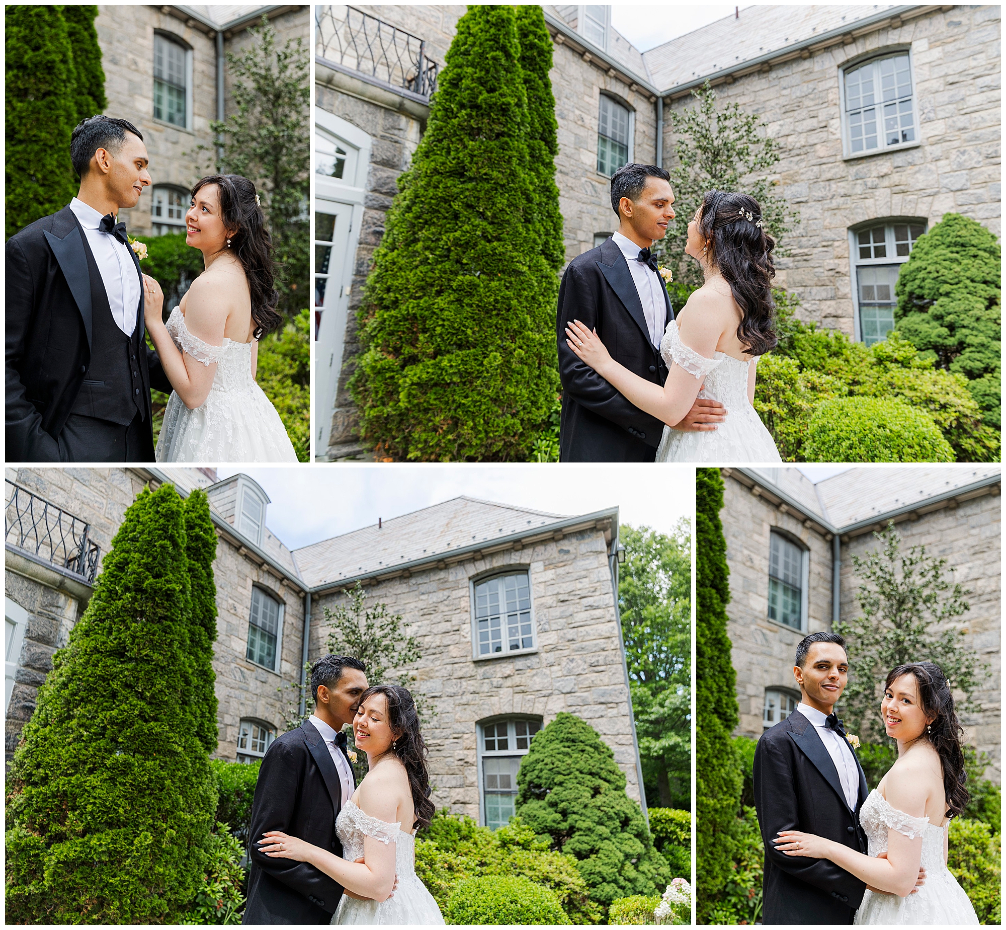 A newlywed couple in formal attire pose together, smiling and gazing at each other, in front of a stone building with large windows and lush greenery in the courtyard.