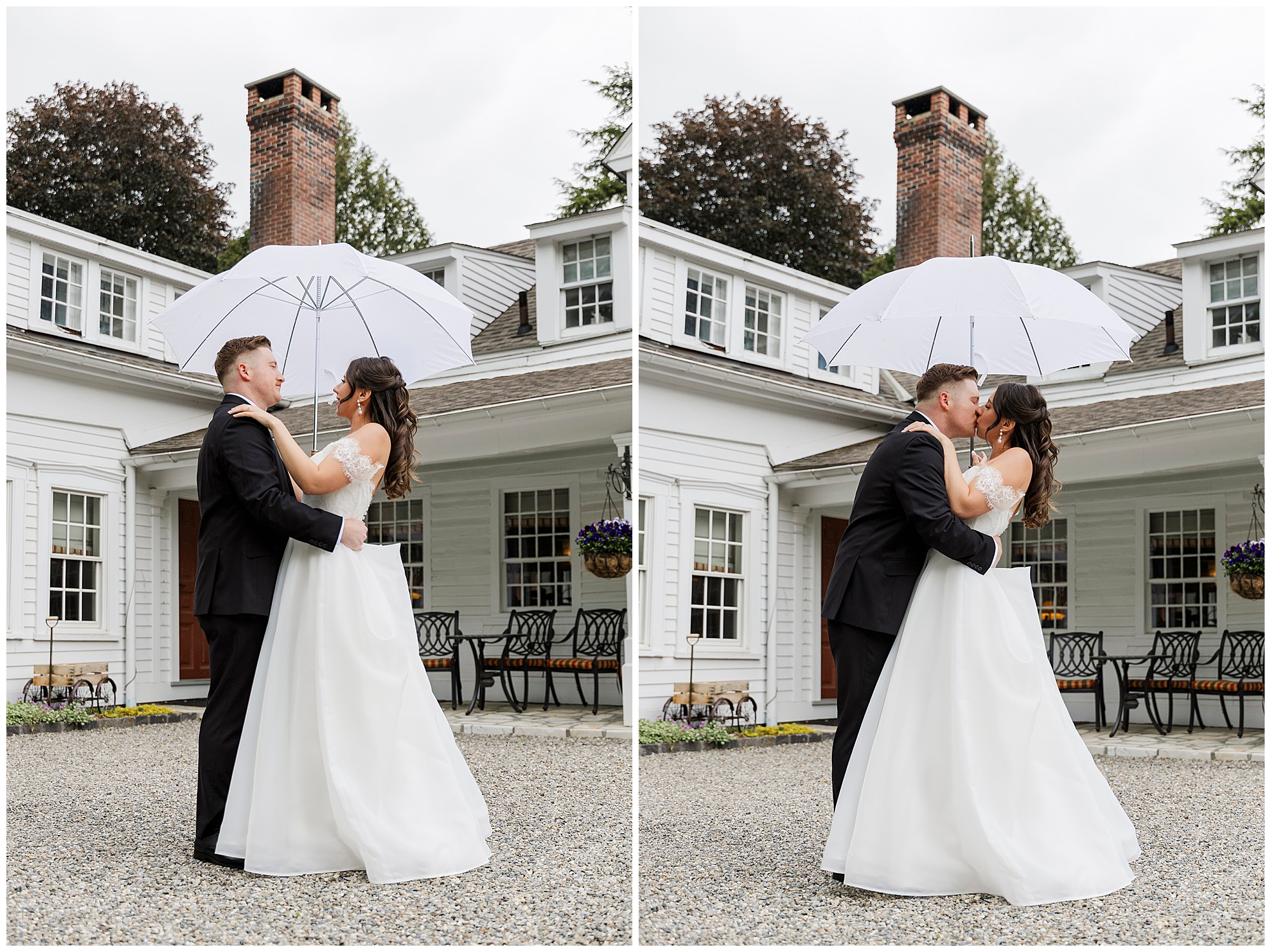 A bride and groom in formal attire embrace and kiss under a white umbrella outside a white house with tall windows and a brick chimney on a cloudy preston barn wedding day.