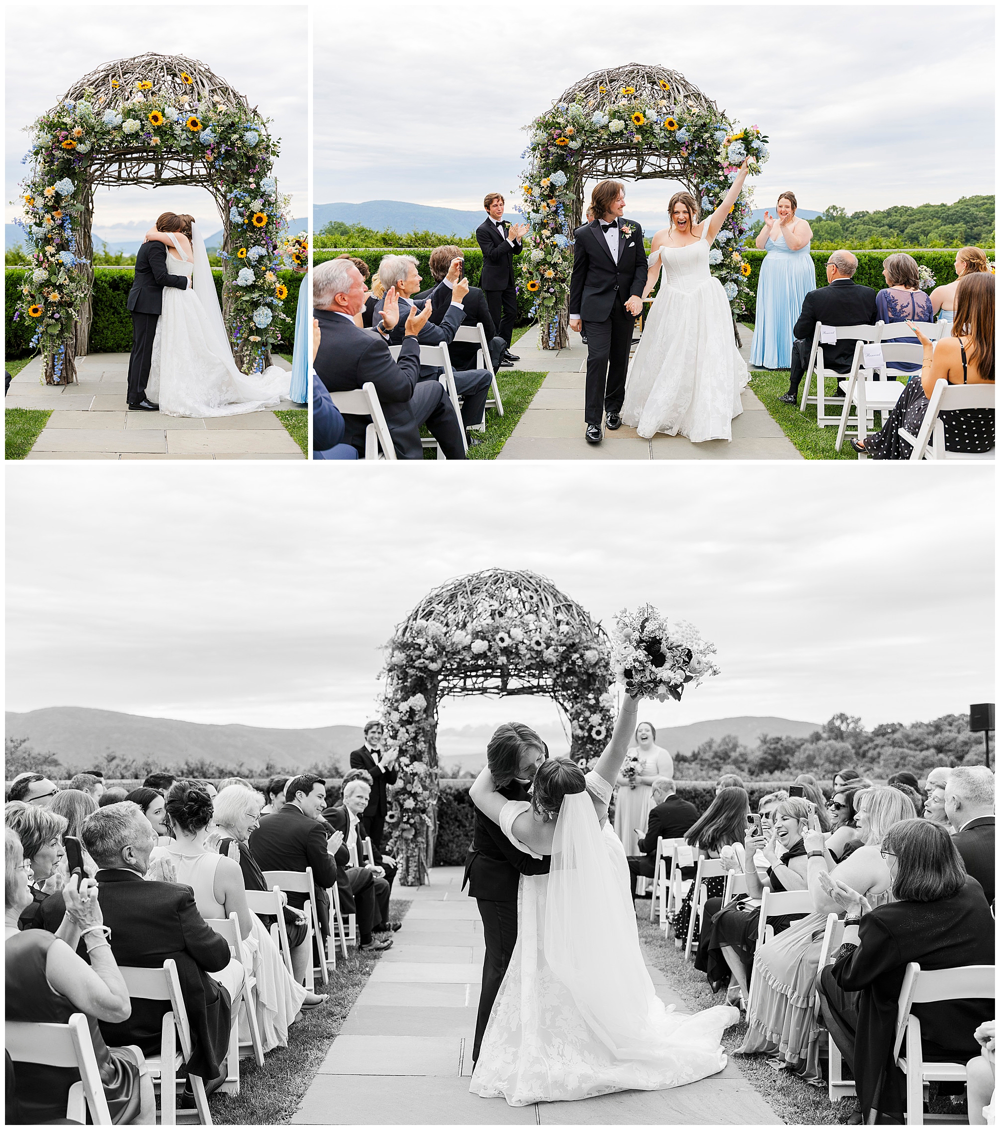 A bride and groom kiss and celebrate under a floral arch during a summer garrison wedding, surrounded by cheering guests and bridesmaids, with scenic mountains in the background.
