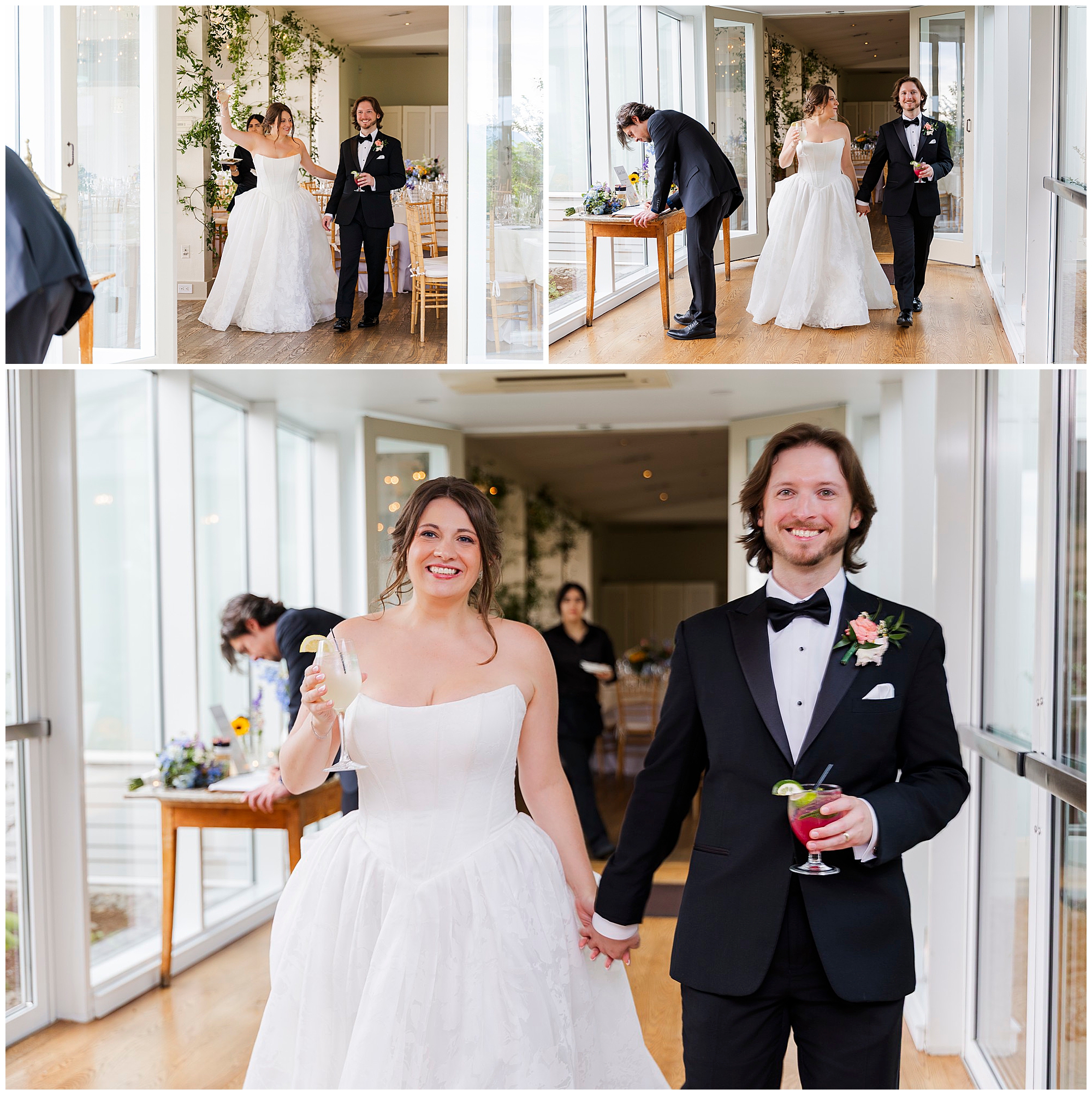 At a summer garrison wedding, a bride in a white gown and groom in a black tuxedo walk hand-in-hand, smiling and holding drinks, in a bright room with large windows; guests and floral decorations fill the background.