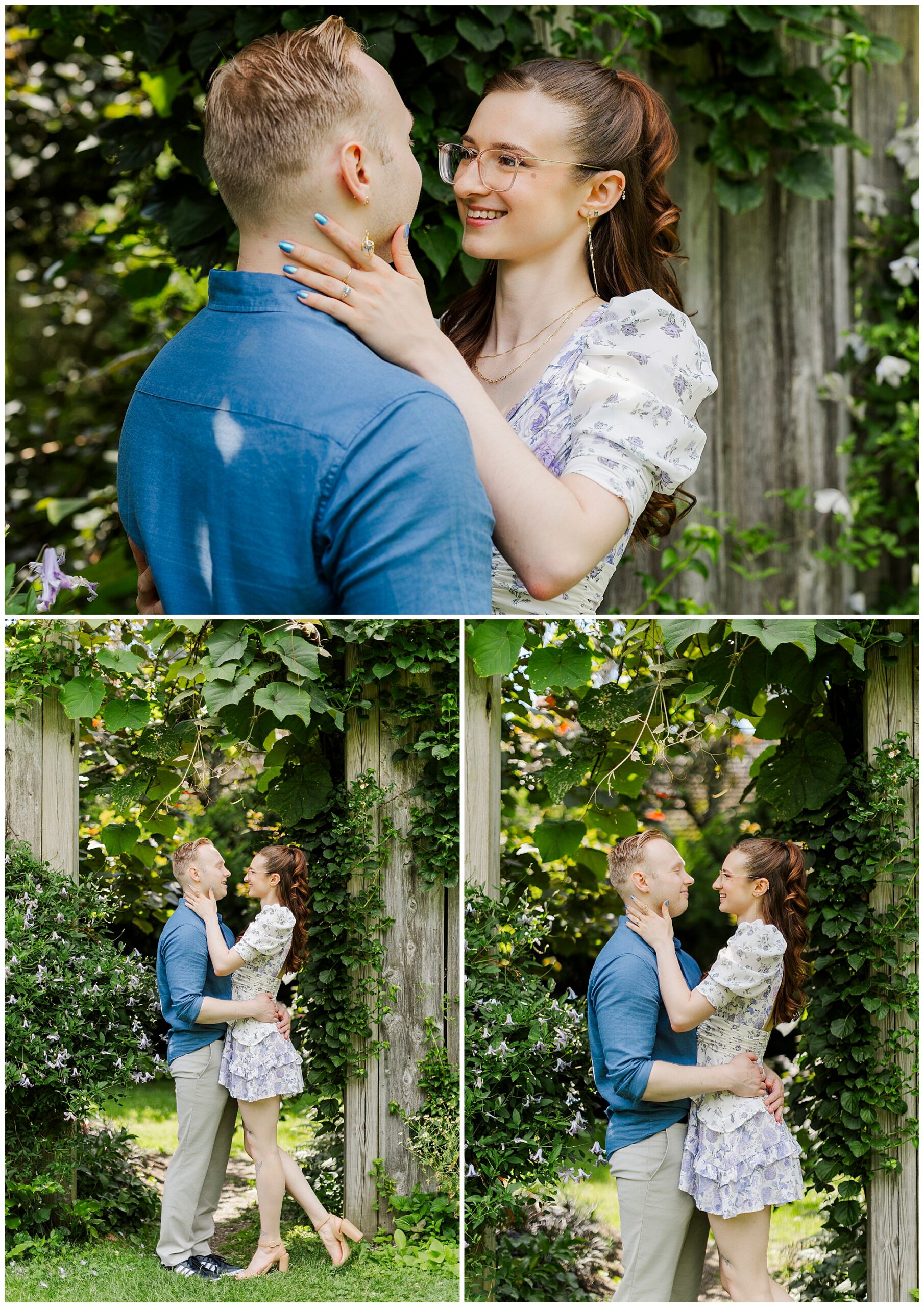 A couple smiles and embraces outdoors by a wooden fence covered in greenery. The woman, in a floral dress, holds the man’s face as he looks at her lovingly—perfect engagement pictures at Stonecrop Gardens in a lush garden setting.