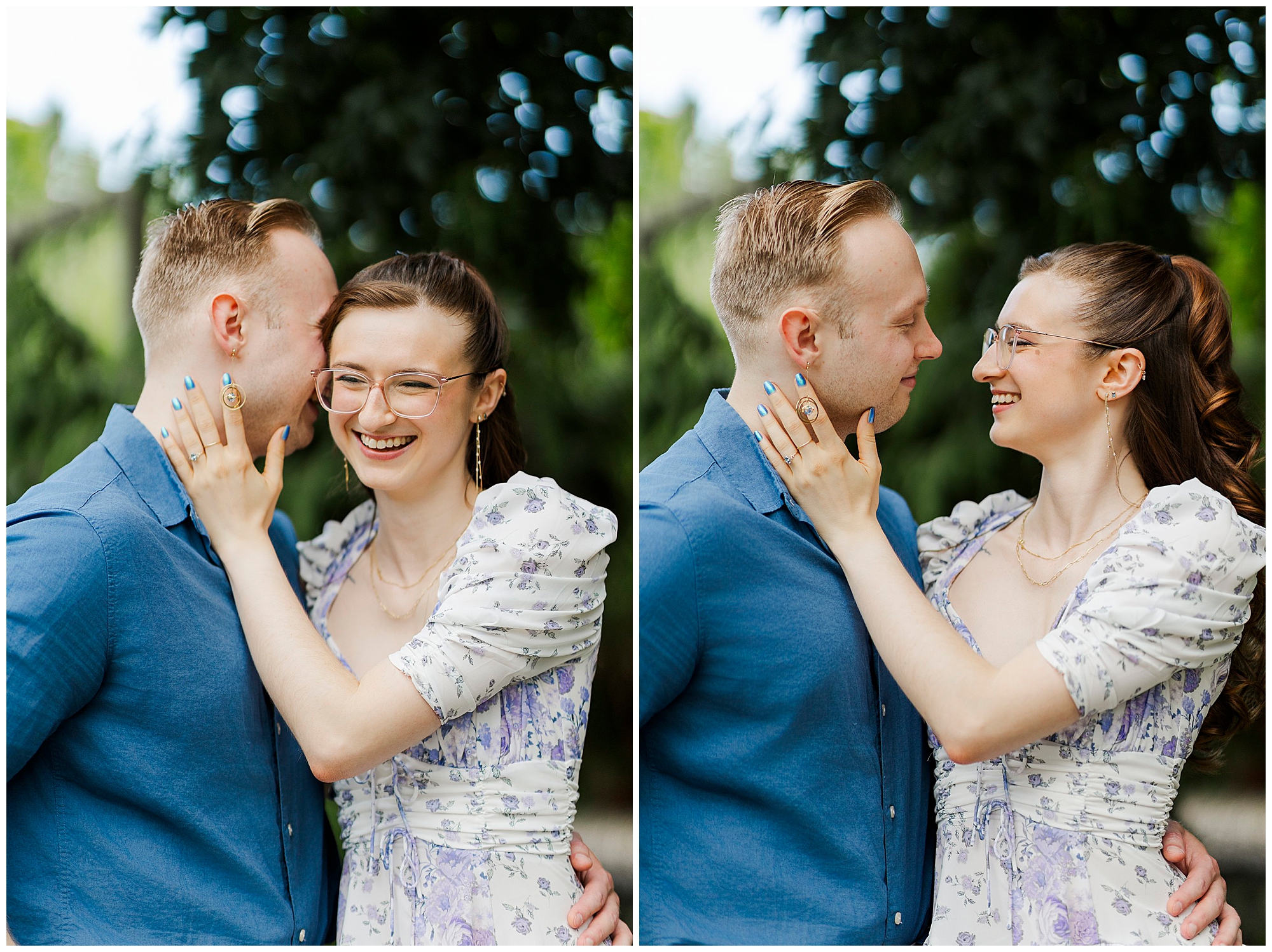 A smiling couple stands close together outdoors, gazing at each other affectionately during their engagement pictures at Stonecrop Gardens. The woman, in glasses and a floral dress, touches the man’s face as he smiles in a blue shirt. Lush green trees blur behind them.
