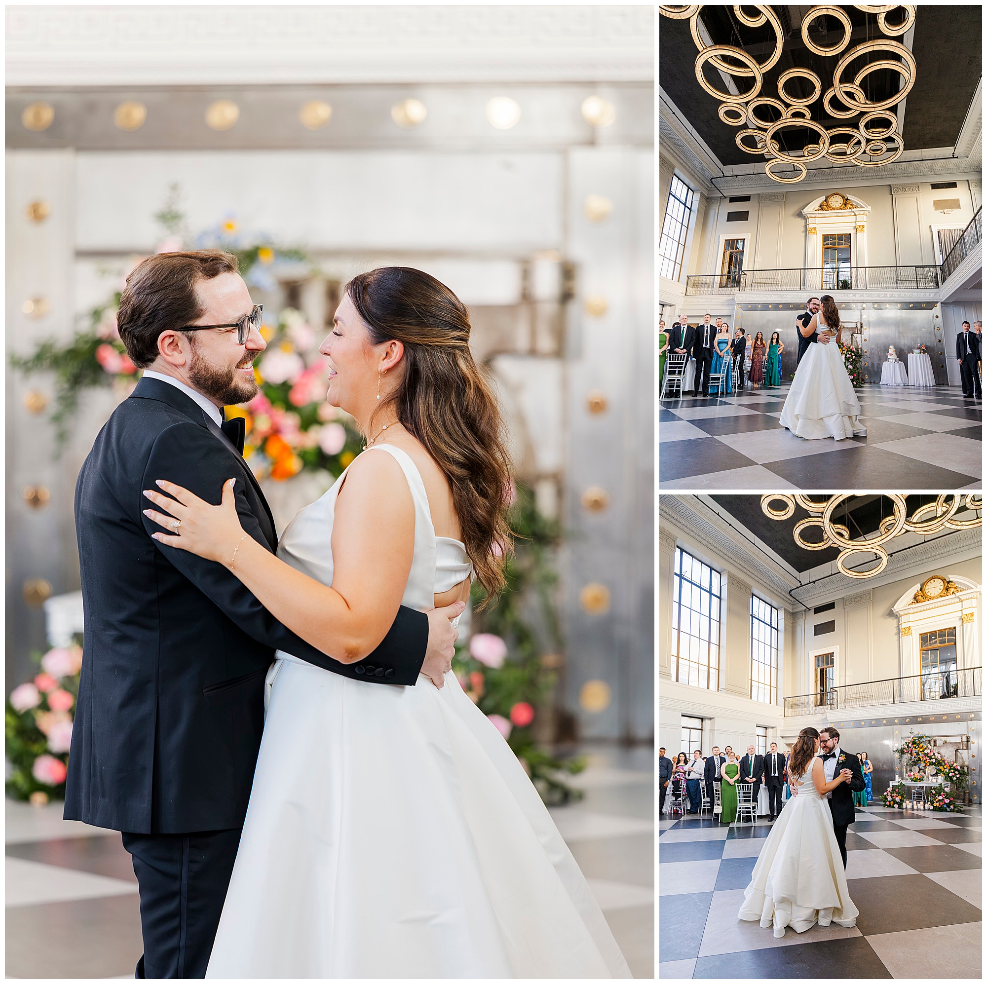 A bride and groom share their first dance in an elegant felina wedding hall with high ceilings, modern circular lights, and large windows. Guests watch as the couple smiles and dances together, surrounded by beautiful floral decorations.