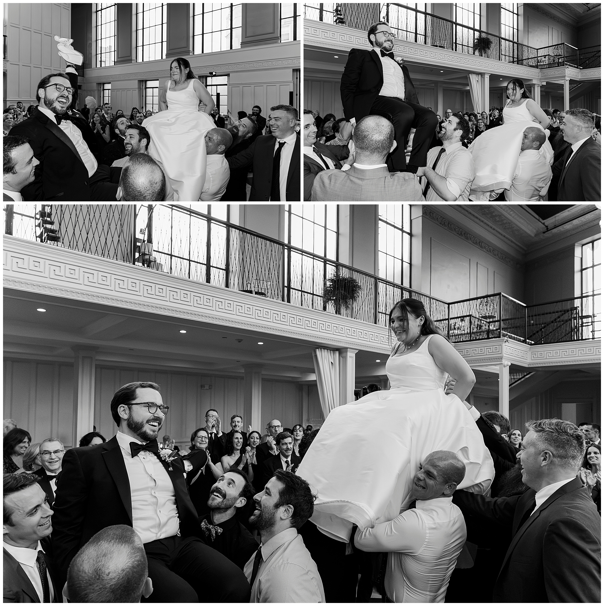 A bride and groom are lifted on chairs by guests at their felina wedding reception, laughing and celebrating in a large, elegant hall filled with people.