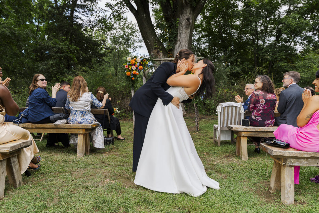Couple shares a dip kiss after their outdoor ceremony at an intimate Blooming Hill Farm wedding