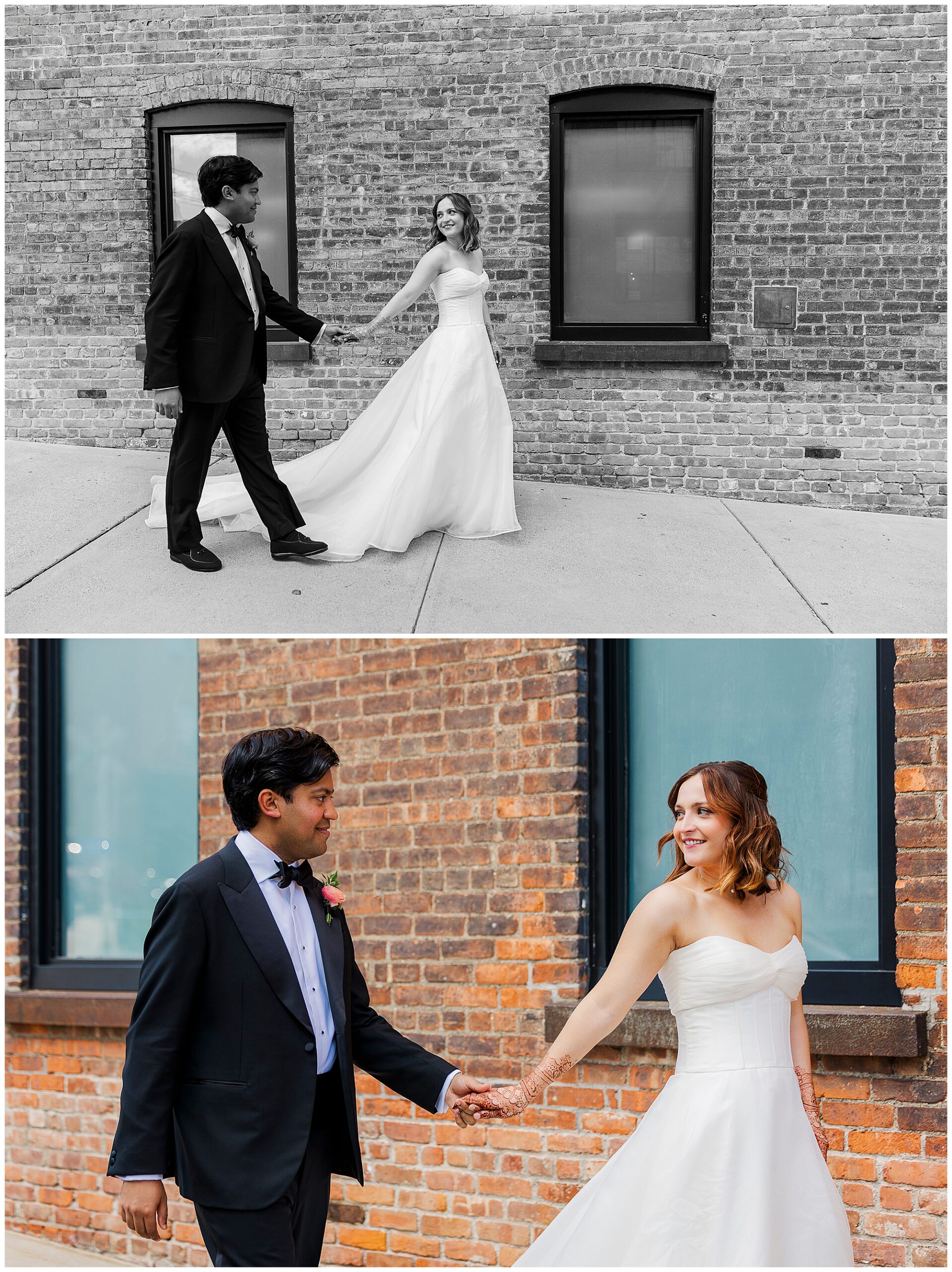 A bride in a strapless white gown and a groom in a black tuxedo hold hands and smile at each other, standing outside against a brick building with large windows, capturing the timeless charm of roundhouse wedding photos.