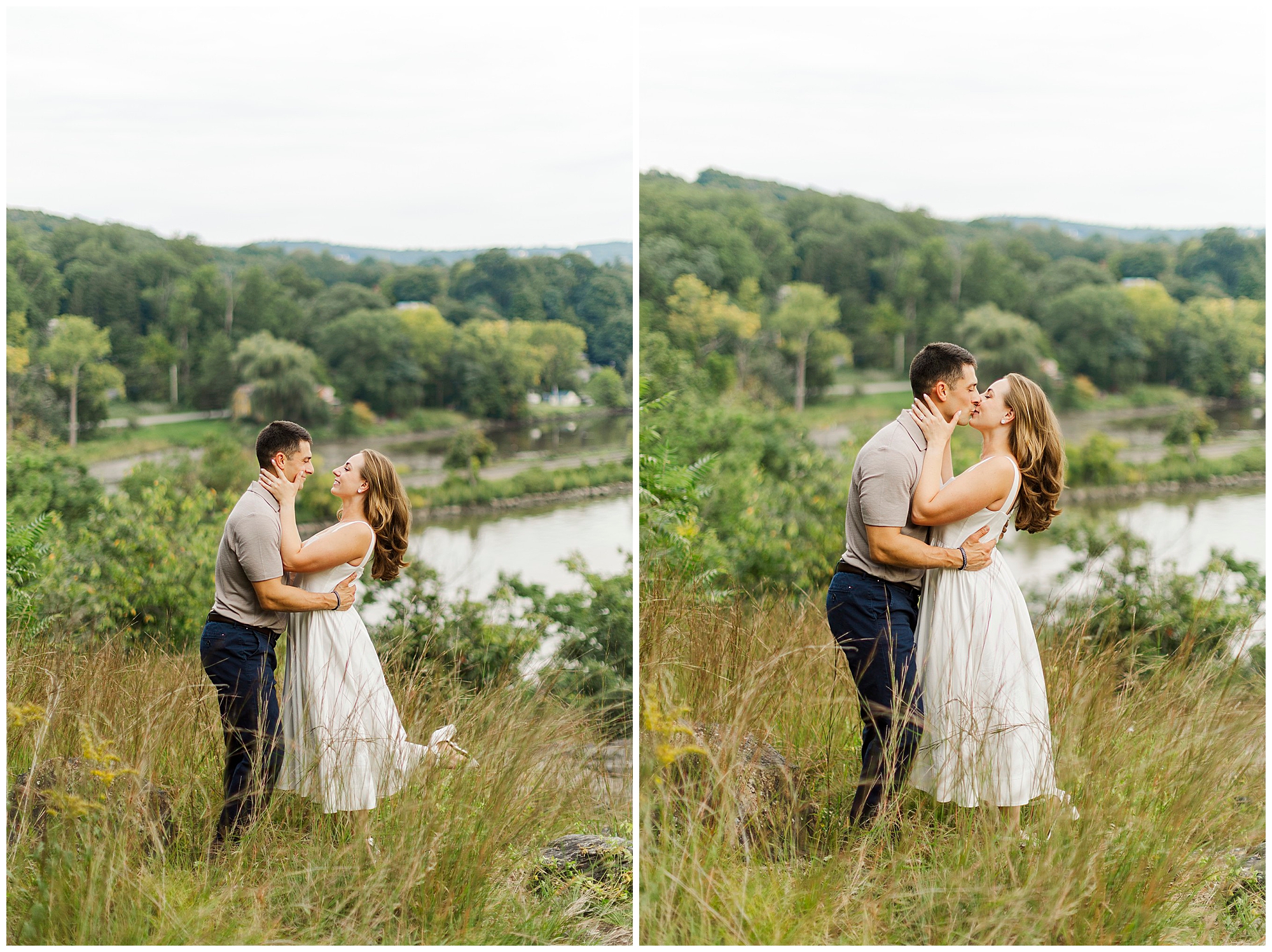 Couple shares an affectionate moment in tall grass by the river, with trees and hills behind them.