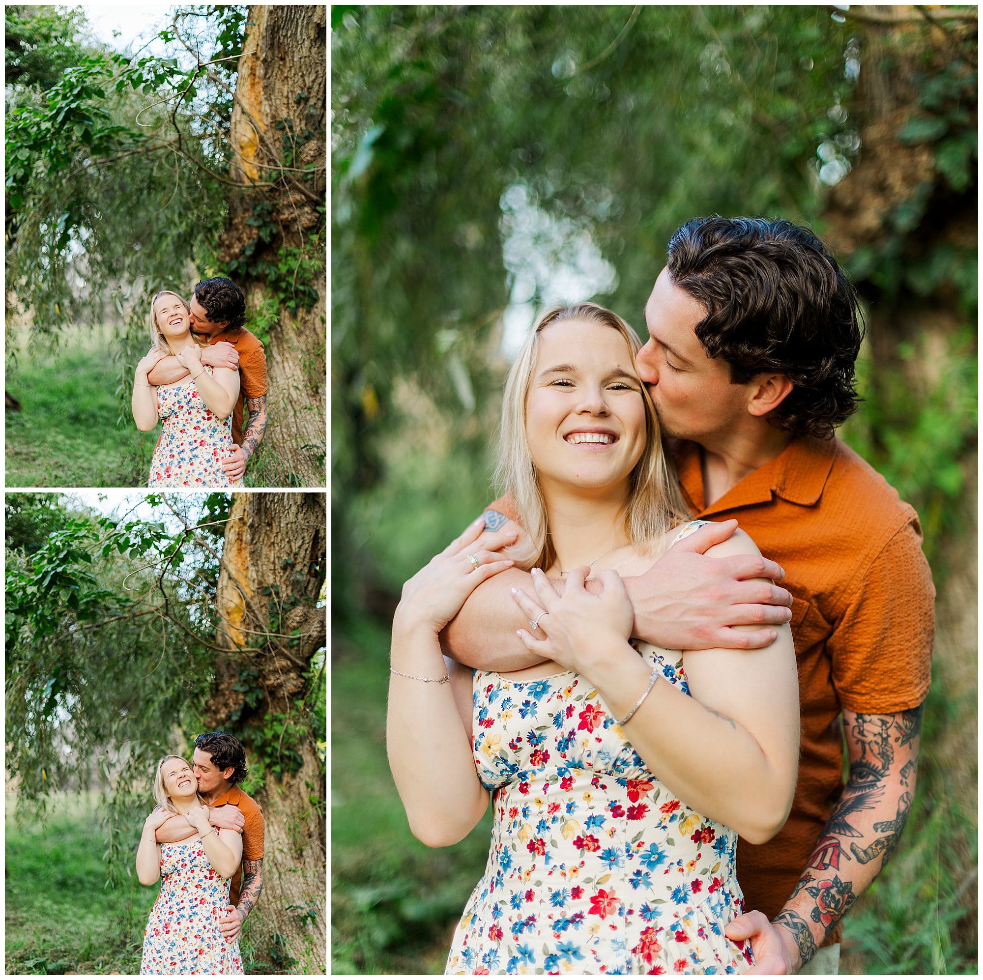 Man in an orange shirt hugs and kisses the woman in a colorful floral dress under a tree, both smiling against lush greenery.