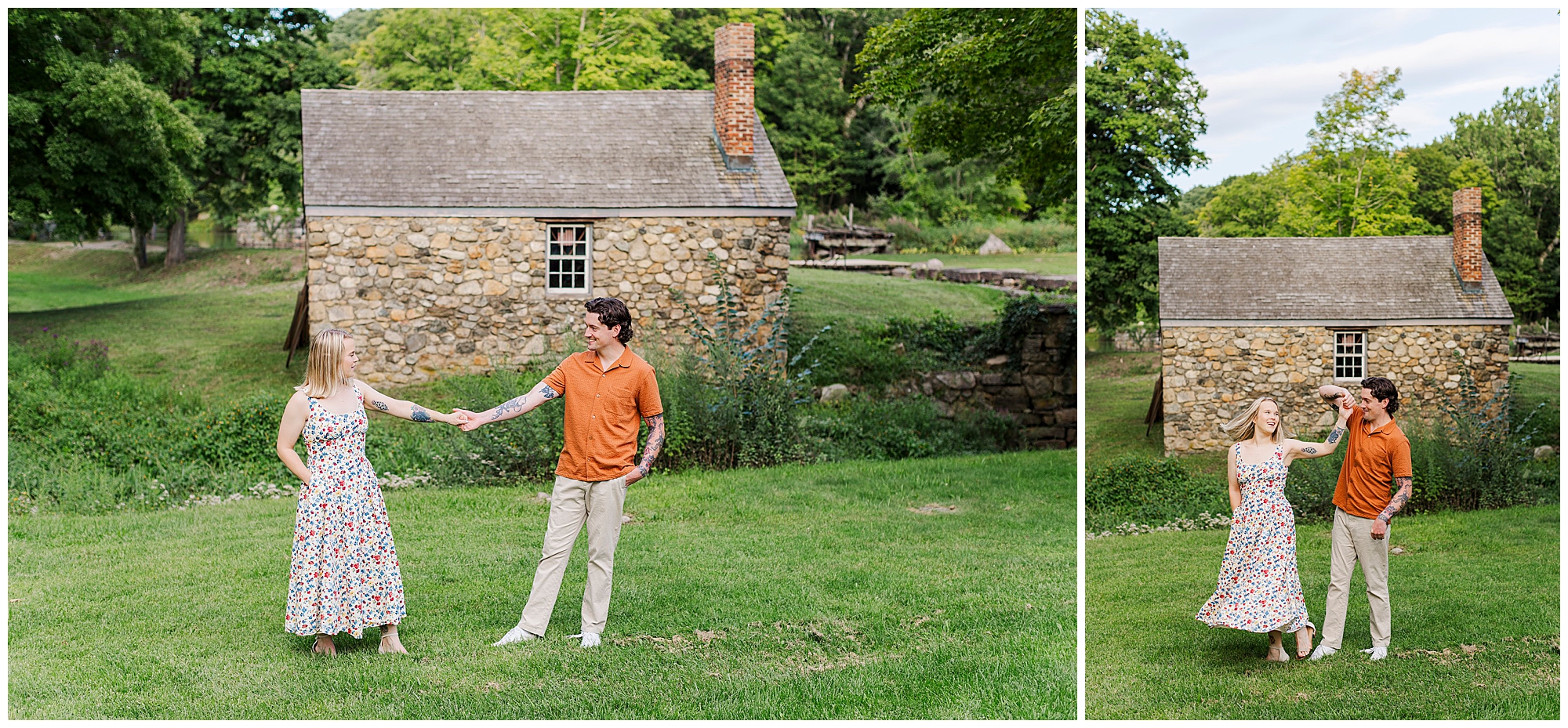 Couple in summer outfits holds hands and dances on the grass in front of a small stone house with a chimney.