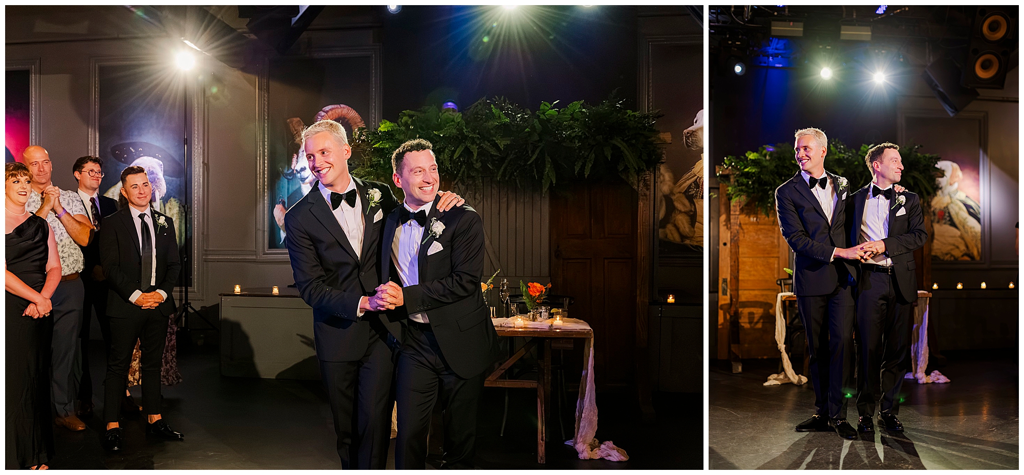 Two grooms in tuxedos smile and hold hands on a dance floor at their Porta Asbury Park wedding, surrounded by guests. The room is warmly lit, decorated with greenery, candles, and draped tables.