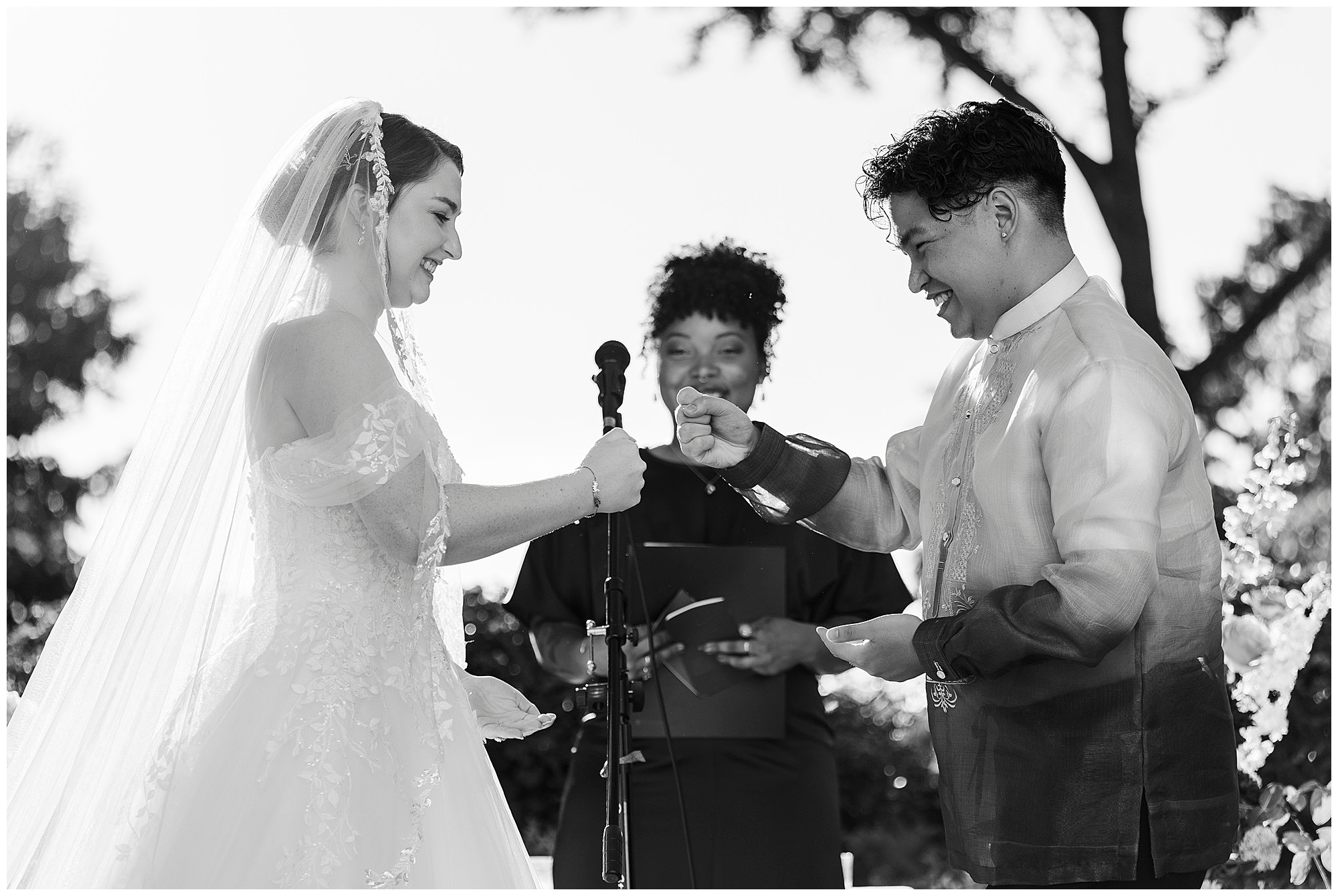 Bride and groom share a fist bump at the altar, both grinning, while the officiant smiles behind them.